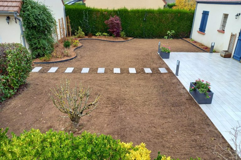 Jardin récemment aménagé avec des dalles blanches et des pots de fleurs.
