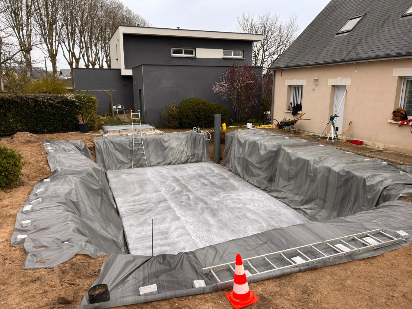 Dalle de fond Terrains creusé pour une piscine, recouvert de bâches et de matériel de construction.