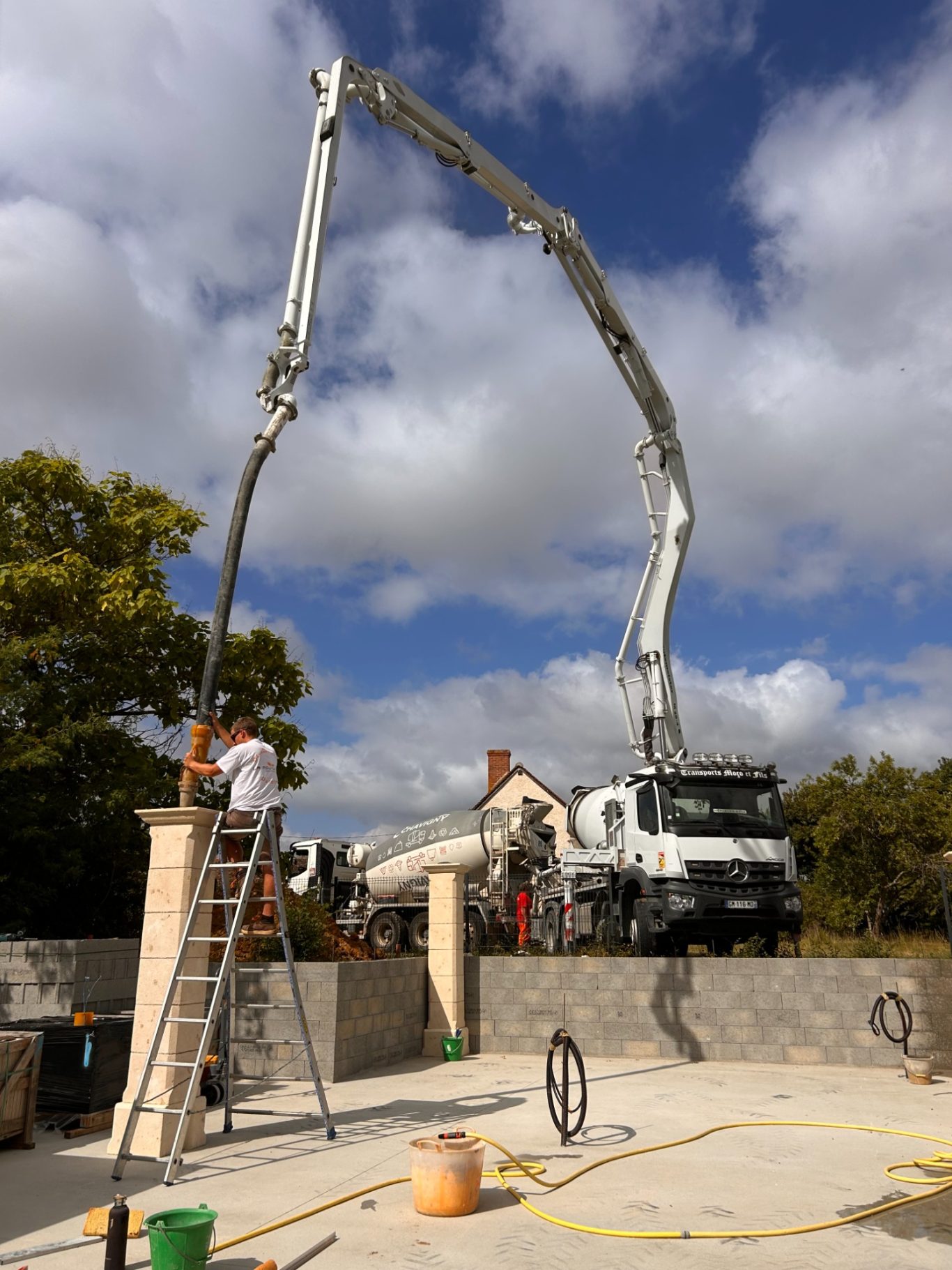 Coulage de pilier Toupie à béton déversant du ciment sur un mur, échafaudage à proximité.