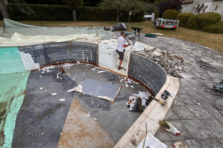 Travail de rénovation d'une piscine avec ouvrier et débris autour.