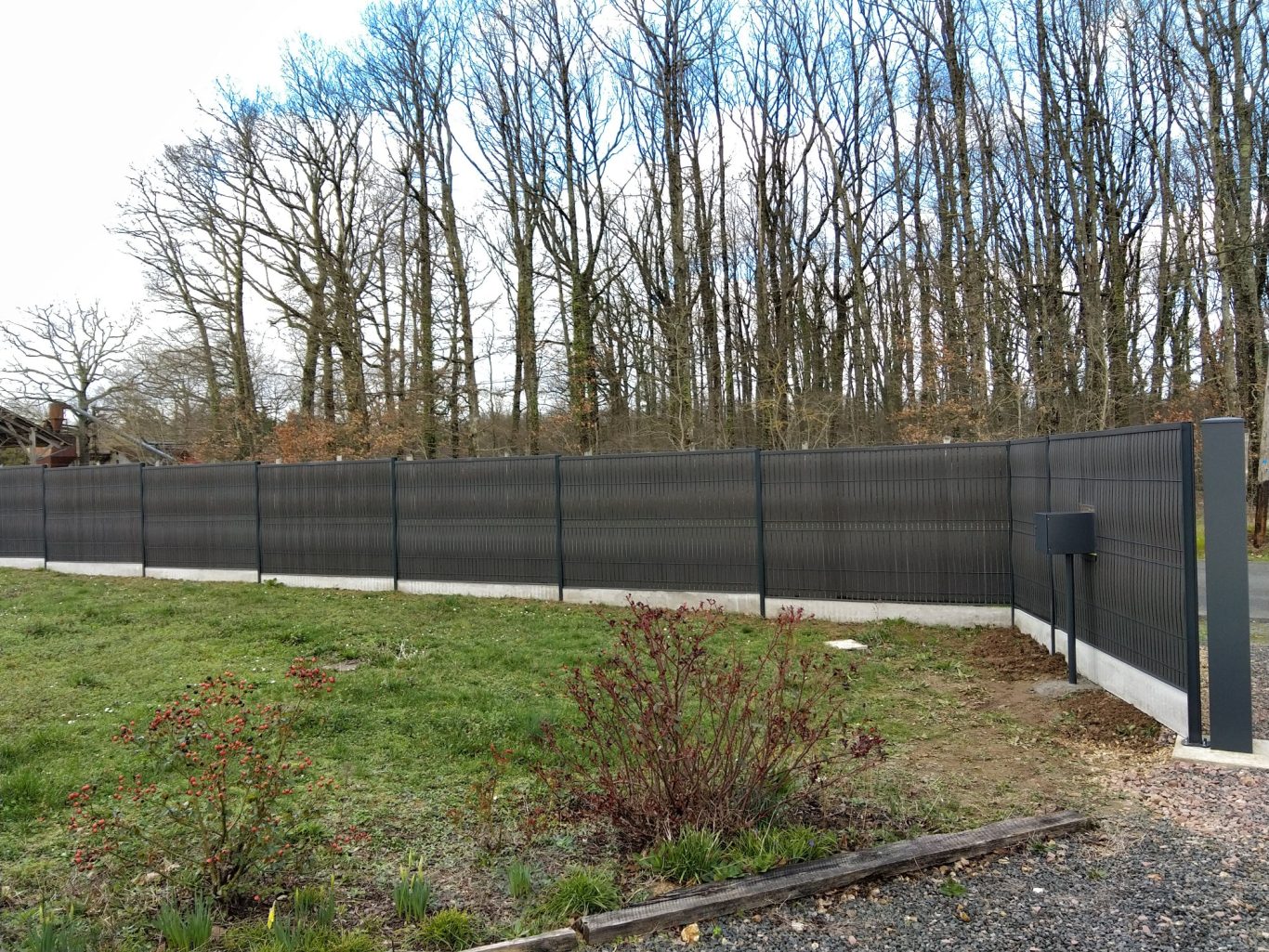 Clôture en panneaux rigides Clôture en grillage noir entourant un espace herbeux et des arbres en arrière-plan.