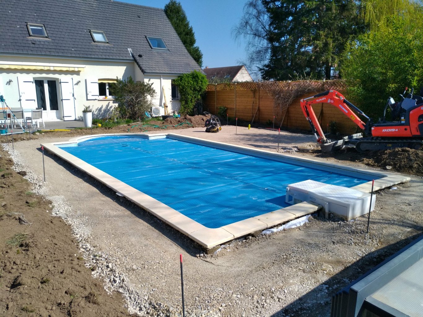 Fond de forme Piscine en construction avec eau bleue, environnée de terre et d'équipement de chantier.