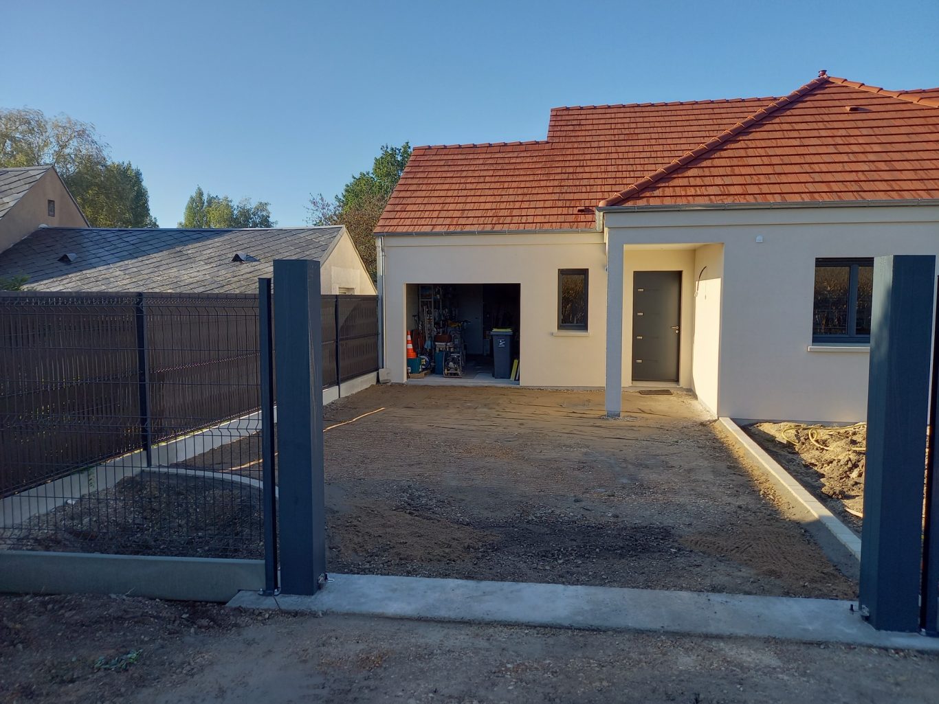 Jonction de la clôture au portail Constructionavec un terrain en cours d'aménagement et des clôtures.