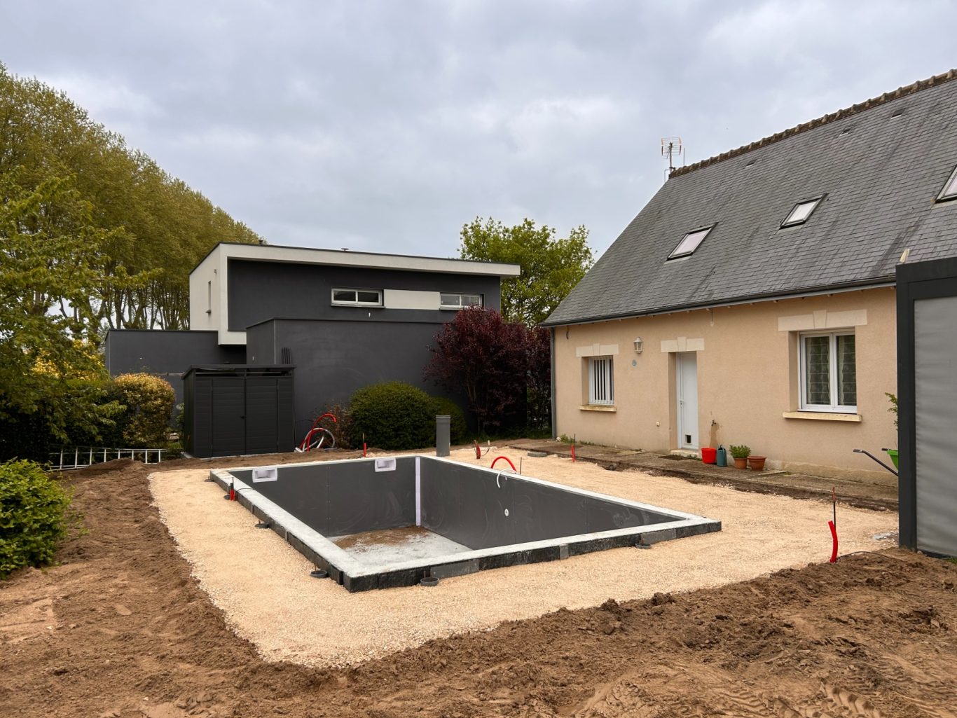 Remblai / Fond de forme calcaire Terrasse en construction avec des fondations et une maison à proximité. Ciel nuageux.