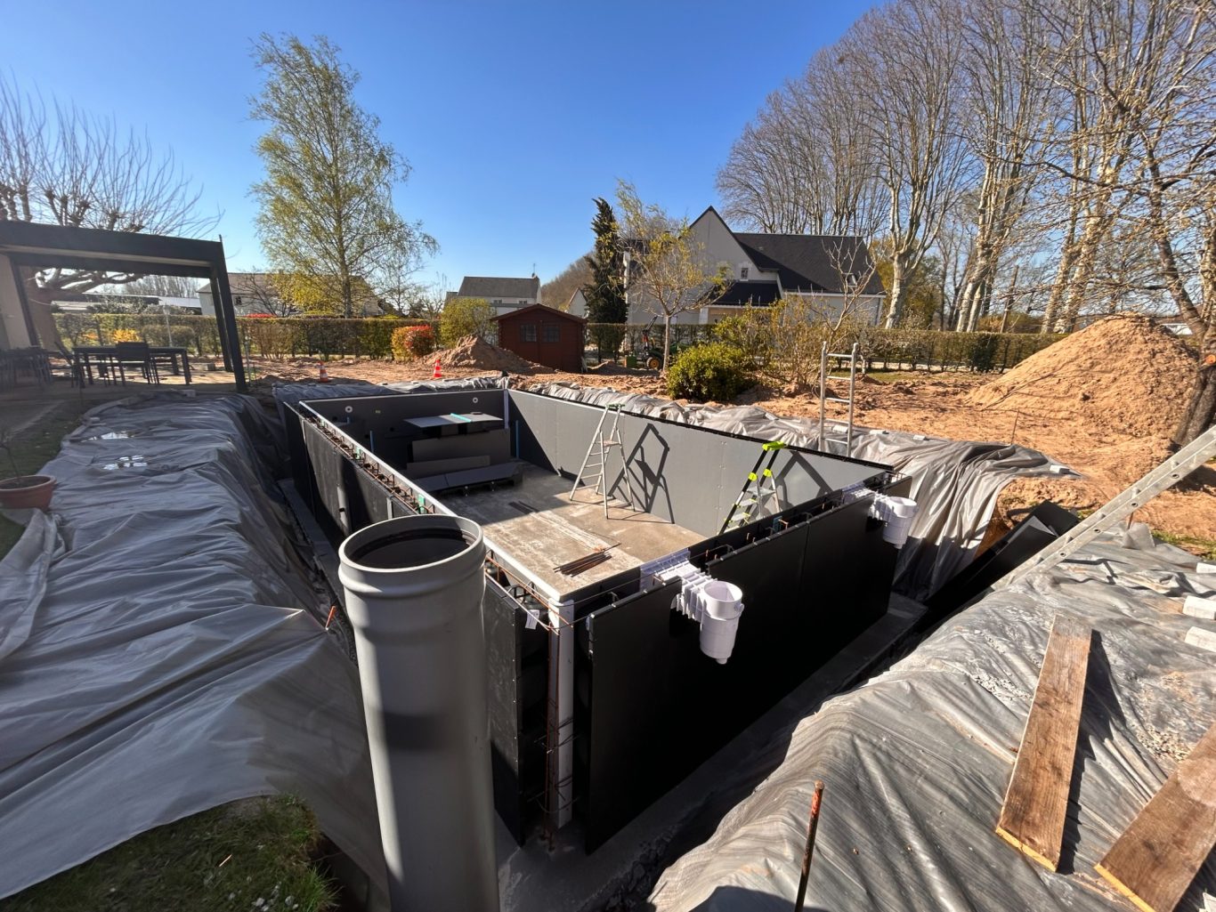 Assemblage des murs / pièces à sceller / puits de décompression Travaux d'excavation avec des bacs en construction dans un jardin.