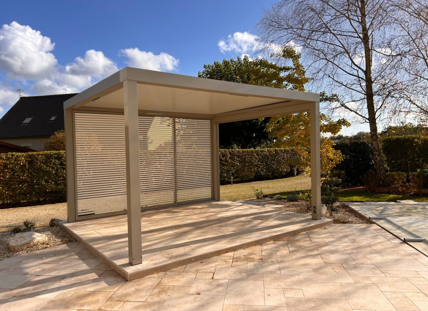 Pergola moderne en béton avec un toit, située sur une terrasse éclairée par le soleil.