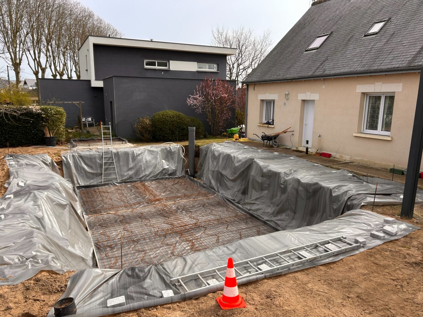 Préparation dalle de fond Terrasse en cours de préparation, recouverte de bâches et armature métallique visible.